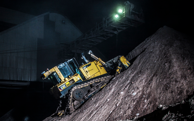 A CAT D6T dozer grading material on a steep slope under floodlights.