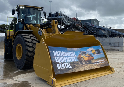 An SER loading shovel parked with a banner strapped across the bucket reading 'Nationwide equipment rental'